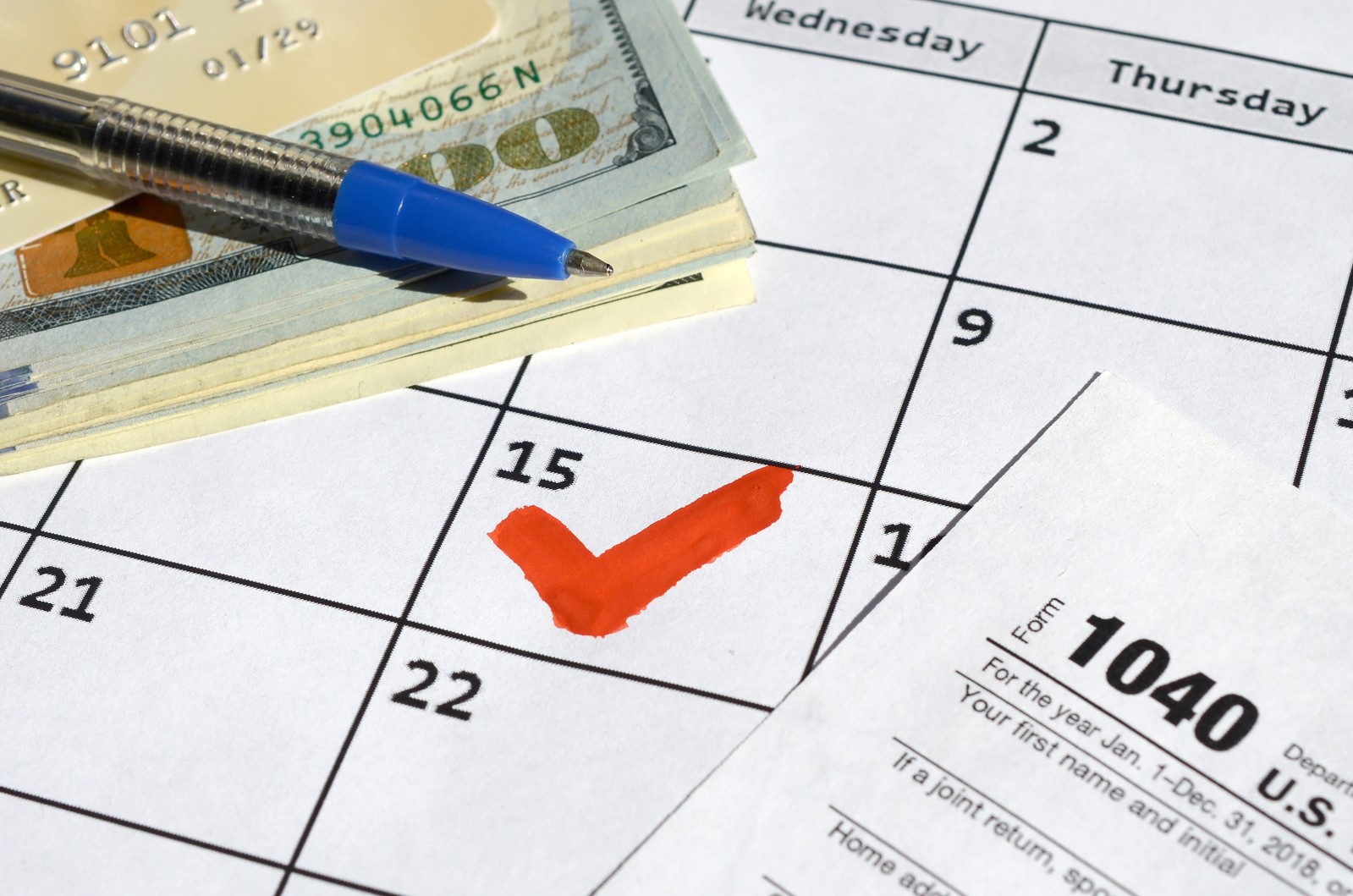 Cash and a 1040 tax form on a calendar