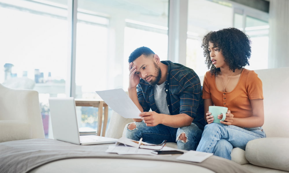 Couple sitting on couch, stressed out over student loan debt