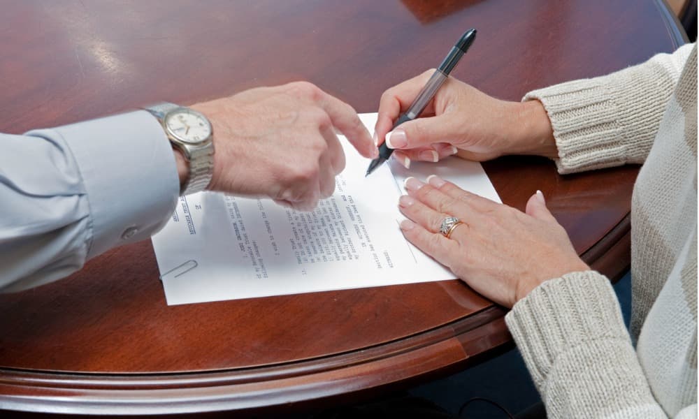 A lawyer showing a client where to sign a beneficiary form.