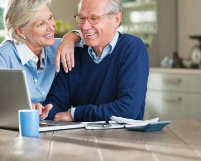 An elderly couple smiling after finding a realistic retirement calculator.